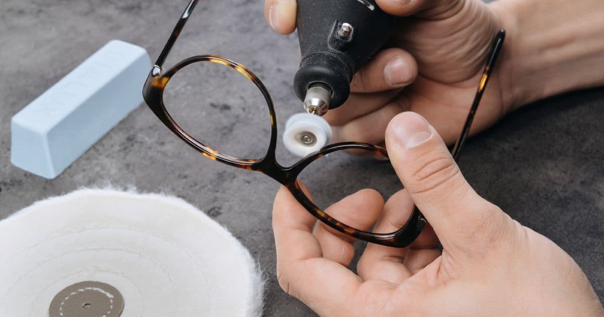 A craftsperson carefully polishing an eyeglass frame